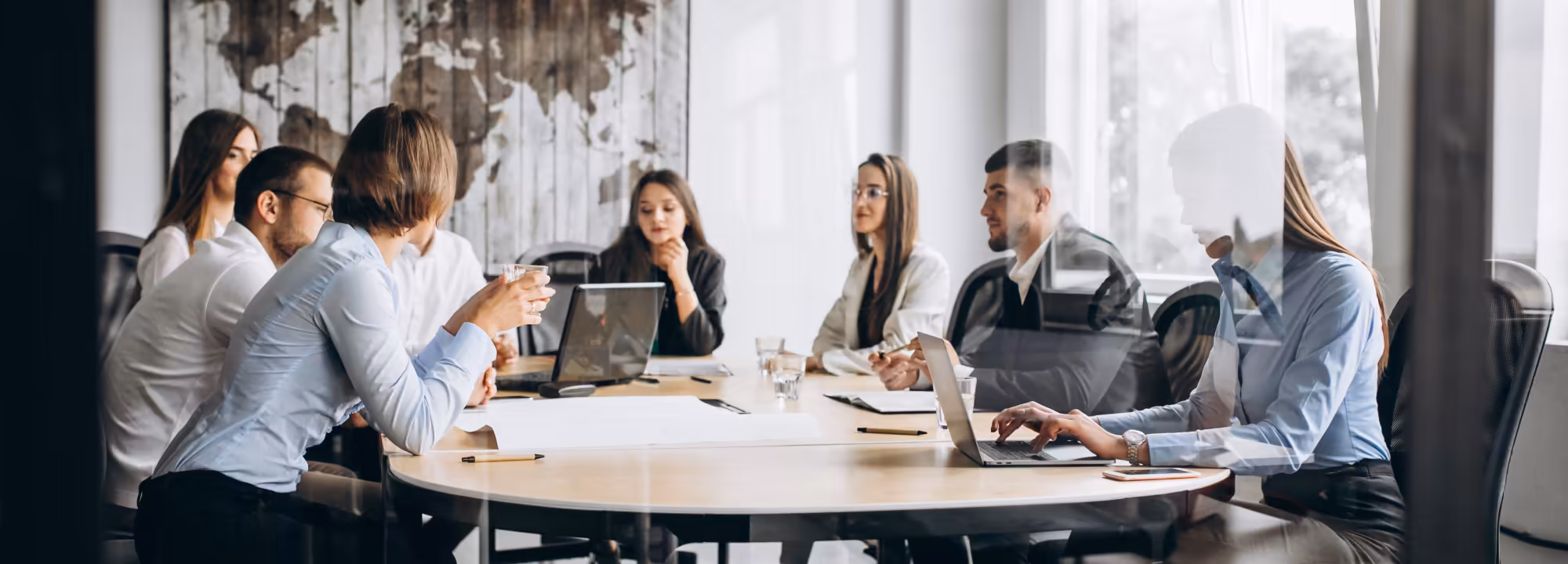 A group of eight people around a boardroom table, having a business meeting